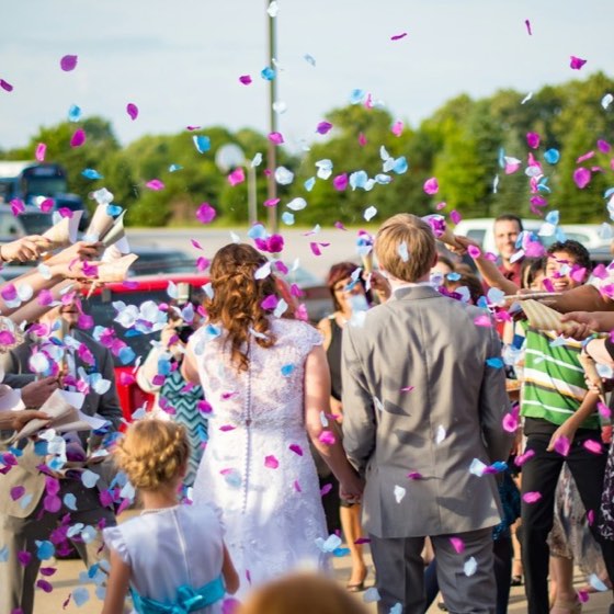 Un couple sort sous une pluie de confettis lancés par ses invités